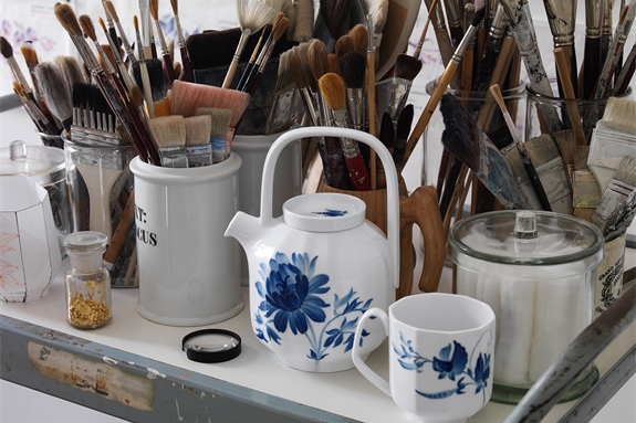 blomst teapot and mug on a table next to a lot of paint brushes in an atelier